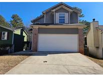 Two-story house with gray siding, brick accents, and a white garage door at 1334 To Lani Farm Rd, Stone Mountain, GA 30083