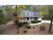 Brick home on wooded lot with large porch and driveway at 1630 Bettis Tribble Gap Rd, Cumming, GA 30040