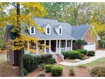 Charming brick home with a welcoming front porch, landscaped yard and beautiful autumn foliage at 1630 Bettis Tribble Gap Rd, Cumming, GA 30040