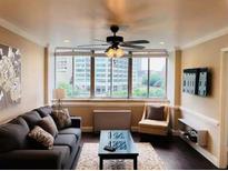 Inviting living room features a ceiling fan, large windows with city views, and dark wood flooring at 215 Piedmont Ne Ave # 710, Atlanta, GA 30308