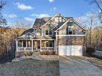 Inviting two-story home with stone accents, a well-manicured lawn, and attached two car garage at 9475 Dunmoore Dr, Cumming, GA 30028