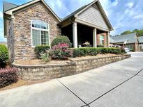 Charming home featuring a stone facade, flower beds, and a welcoming covered porch at 4140 Lanier Ridge Walk # 104, Cumming, GA 30041
