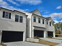 Three-unit townhome building, featuring white brick, black garage doors, and a modern design at 1942 Westwind Street (Lot 134), Lawrenceville, GA 30043