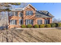 Brick two-story house with a landscaped lawn and mature trees at 5480 Landseer Way, Cumming, GA 30040