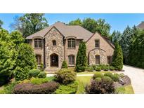 Brick and stone two-story home with landscaped lawn and driveway at 830 Camden Park Ne Ct, Atlanta, GA 30342