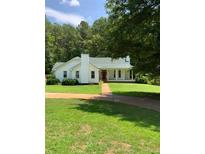 White house with green roof, large yard, and trees at 3639 Holly Springs Rd, Rockmart, GA 30153