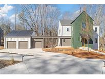 Modern home showcasing a three-car garage, distinctive green siding, and connecting walkway at 135 Cedarwood Ln, Roswell, GA 30075