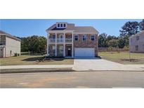 Two-story brick home with balcony, attached garage, and landscaped yard at 205 Chiswick Loop, Stockbridge, GA 30281