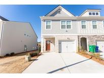 Two-story townhome with gray siding, white garage door, and landscaping at 1884 Plainsboro Dr, Lithonia, GA 30058