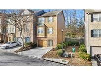 Tan three-story townhome with a brick facade, attached garage, and landscaping at 2793 Keystone Ave, Lithonia, GA 30058