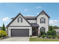 Two-story house with gray and white siding, dark garage doors, and landscaped yard at 3280 Buffington Ln, Cumming, GA 30040