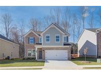 Two-story brick and gray siding home with a white two-car garage and landscaping at 277 Tulip Dr, Covington, GA 30016