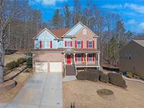 Brick and blue two-story house with red accents, front porch, and driveway at 753 Win West Xing, Auburn, GA 30011