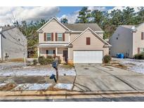 Two-story house with beige siding, brown accents, and a white garage door at 7369 Saint Peter Way, Fairburn, GA 30213