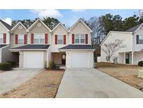 Tan siding townhouse with red shutters, two-car garage, and landscaping at 6977 Gallant Se Cir # 8, Mableton, GA 30126