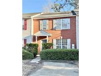 Brick two-story townhome with gray door, shutters, and manicured landscaping at 2884 Norfair Loop, Lithonia, GA 30038