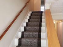 Carpeted staircase with wooden handrails leads to the upper level of this home at 345 Lexington Dr, Lawrenceville, GA 30046