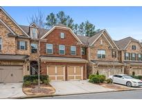 Brick front three-story townhome with two-car garage and landscaped yard at 262 Senna St, Marietta, GA 30064