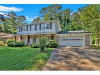 Two-story home with a brick facade, two-car garage, shutters, and lush green lawn and mature landscaping at 1354 Drayton Woods Dr, Tucker, GA 30084