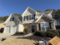 Two-story house with stone and shingle accents, two-car garage, and manicured landscaping at 3024 Cooper Woods Ln, Loganville, GA 30052
