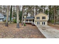 Updated yellow house with a covered porch and driveway, nestled among tall trees at 368 Sumer Ln, Douglasville, GA 30134