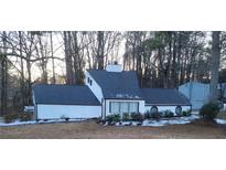 White house with dark gray roof, surrounded by trees, some snow on the ground at 3123 Oak Dr, Marietta, GA 30066