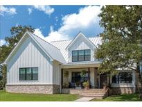 Two-story farmhouse with metal roof, white siding, and brick accents at 1440 Fairview Rd, Ellenwood, GA 30294