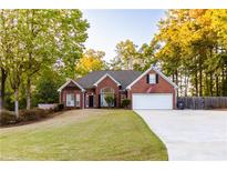 Brick home with attached garage, American flag, and large yard at 2063 Emily Dr, Social Circle, GA 30025