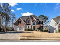 Brick two-story house with three-car garage and landscaped yard at 3845 Montvale Xing, Cumming, GA 30041