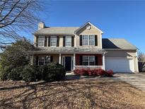 Two-story house with a beige exterior, black shutters, and a red brick accent at 1563 Nicole Ridge Ct, Loganville, GA 30052