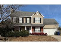 Two-story house with beige siding, a two-car garage, and landscaping at 1563 Nicole Ridge Ct, Loganville, GA 30052