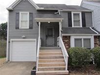 Charming two-story home with gray siding, attached garage, and inviting front entrance with stairs at 390 Lakeridge Ct, Riverdale, GA 30274