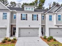 Modern two-story townhome with gray and white brick exterior, two-car garage, and landscaping at 5455 Rock Place Ct # 40, Norcross, GA 30093