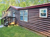 Charming log cabin with a red metal roof and a well-manicured lawn at 218 Helen Rd, Covington, GA 30016