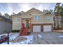 Two-story house with beige siding, two-car garage, and a red staircase at 113 Omega Ct, Dallas, GA 30157