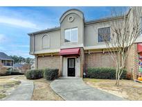 Two-story townhome with red awning and manicured landscaping at 3301 Henderson Mill Rd # R1, Chamblee, GA 30341