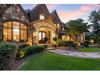 Stunning brick and stone home with arched entryway, manicured lawn, and lush landscaping at 4874 Kettle River Pt, Suwanee, GA 30024