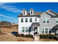 Two-story townhome with gray and white siding, a front porch, and landscaping at 2709 Richmond Row Dr, Suwanee, GA 30024