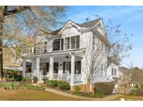Charming two-story white home featuring a welcoming front porch, black shutters and professionally landscaped yard at 1399 Knob Hill Se Ct, Atlanta, GA 30316