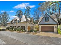 Charming home with a European-inspired design, detailed with an arched garage and manicured landscaping at 23 Paces West Dr, Atlanta, GA 30327