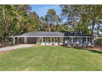 Newly renovated ranch home with gray siding, spacious lawn, and long driveway at 1352 Jennie Sw Ln, Lilburn, GA 30047