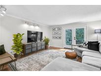 Spacious living room with hardwood floors, comfy sectional sofa, and access to balcony at 3478 Essex Ave, Atlanta, GA 30339