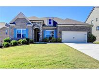 Brick home with landscaped yard, attached garage, and blue shutters at 4144 Hawking Dr, Suwanee, GA 30024