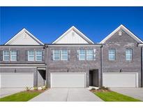 Three-unit townhome building with gray brick exterior, attached garages, and small front yards at 237 Epping St # 89, Stockbridge, GA 30281