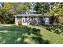 Charming single story home with a well-manicured lawn, mature trees, and a welcoming front porch and door at 1003 Springdale Dr, Marietta, GA 30062