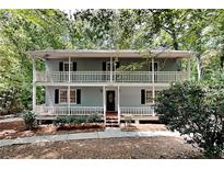 Charming home featuring a classic two-story design with dual-level balconies and a surrounding wooded landscape at 3337 Devaughn Ne Dr, Marietta, GA 30066