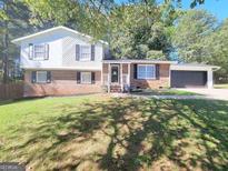 Brick house with attached garage and landscaped lawn at 208 Willows Ct, Riverdale, GA 30274