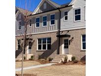 Two story townhome with light gray and beige exterior, landscaping and walkway at 1238 Ainsworth Aly # 38, Sugar Hill, GA 30518