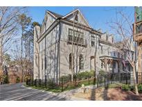 Three-story townhome with gray brick exterior, black fence, and manicured landscaping at 160 Cricket Ln, Alpharetta, GA 30009