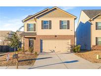 Two-story house with a beige exterior, brick bottom, and a two-car garage at 1597 Culpepper Ln, Mcdonough, GA 30253